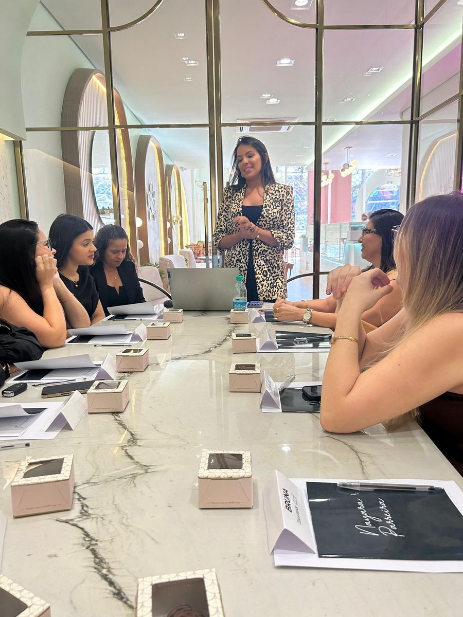 Nayara conduzindo um treinamento de vendas com empresárias ao redor de uma mesa